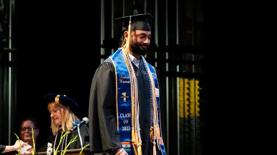 A student walking across the commencement stage