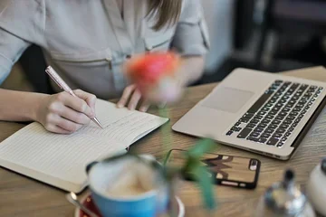 A person at a computer taking notes