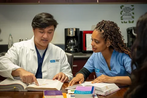 Two nursing students looking at books