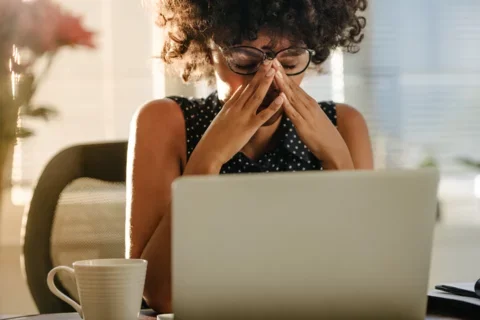 A woman in front of a computer looking stressed out.