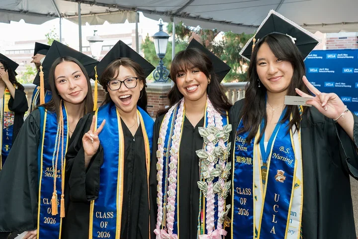Four nursing students wearing their cap and gowns at the commencement ceremony.