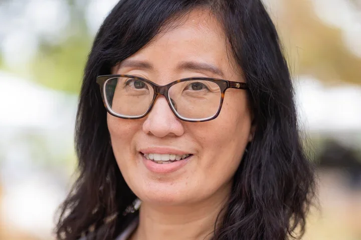 Dr. Suwen Pan wearing black shirt, white lab coat, and glasses.