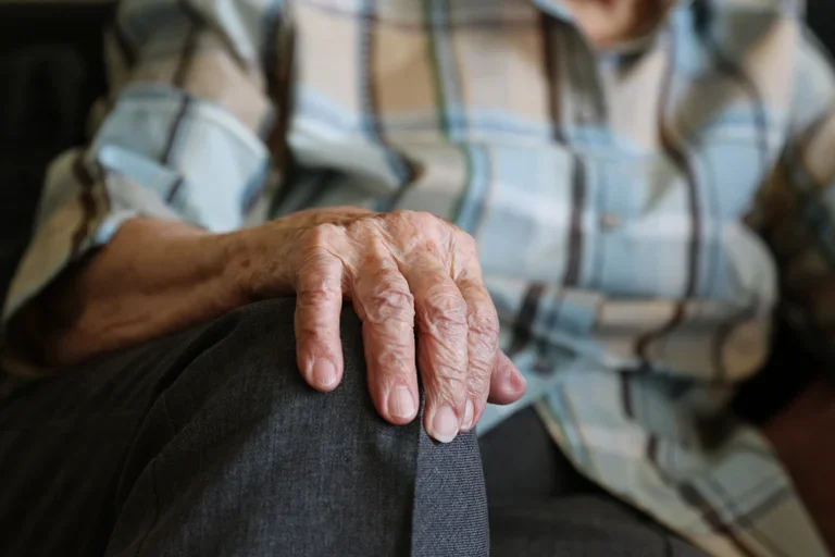 A closeup of an elderly woman's hand on her knee. 