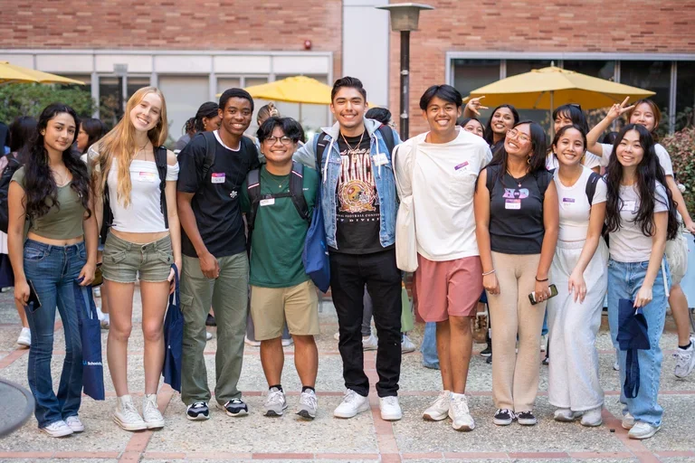 Students standing up and smiling taking a group picture