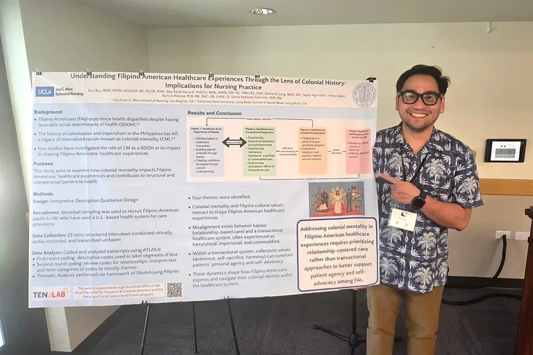 Paolo Roca standing with a research poster he presented at a recent conference.