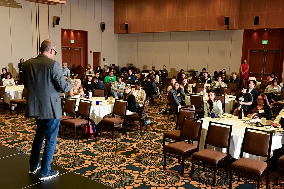 An attendee presenting his research to a seated audience.