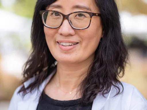 Dr. Suwen Pan wearing black shirt, white lab coat, and glasses.