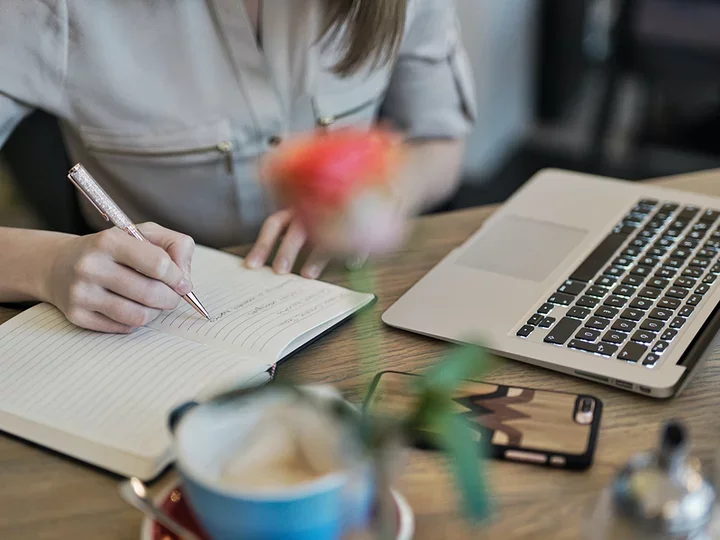 A person sitting at a computer taking notes