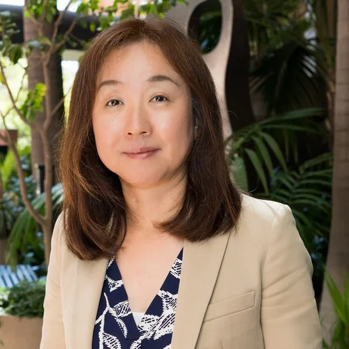 Mayumi Saiki wearing a tan suit and black and white print shirt.