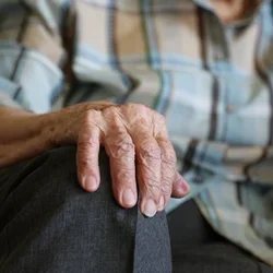 A closeup of an elderly woman's hand on her knee. 