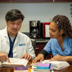 Two nursing students looking at books