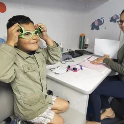 A child sitting with a provider and trying on glasses