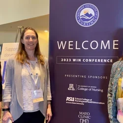 Three students standing at the WIN Conference welcome sign