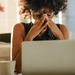 A woman in front of a computer looking stressed out.