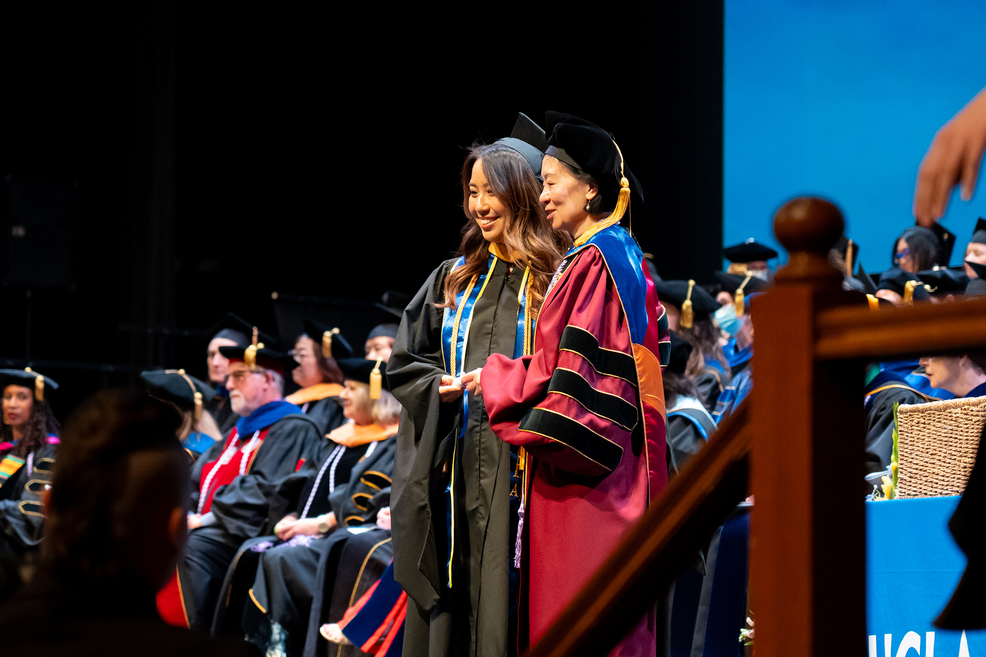 A student on stage with Dean Lin Zhan at commencement