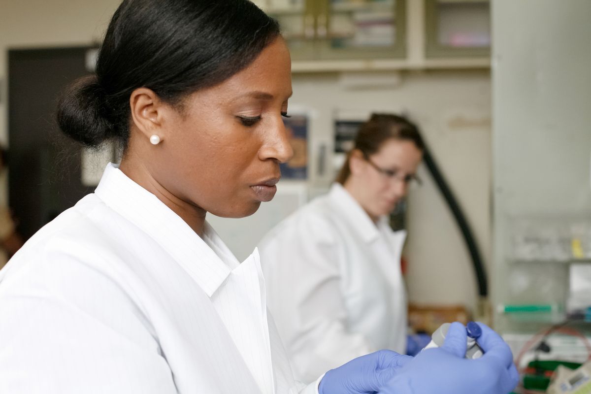 Woman in a lab coat wearing gloves, conducting research