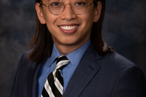 Man with long hair and glasses wearing a suit