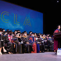 UCLA Nursing faculty on stage at the 2022 Commencement Ceremony. Dean Lin Zhan is at the podium